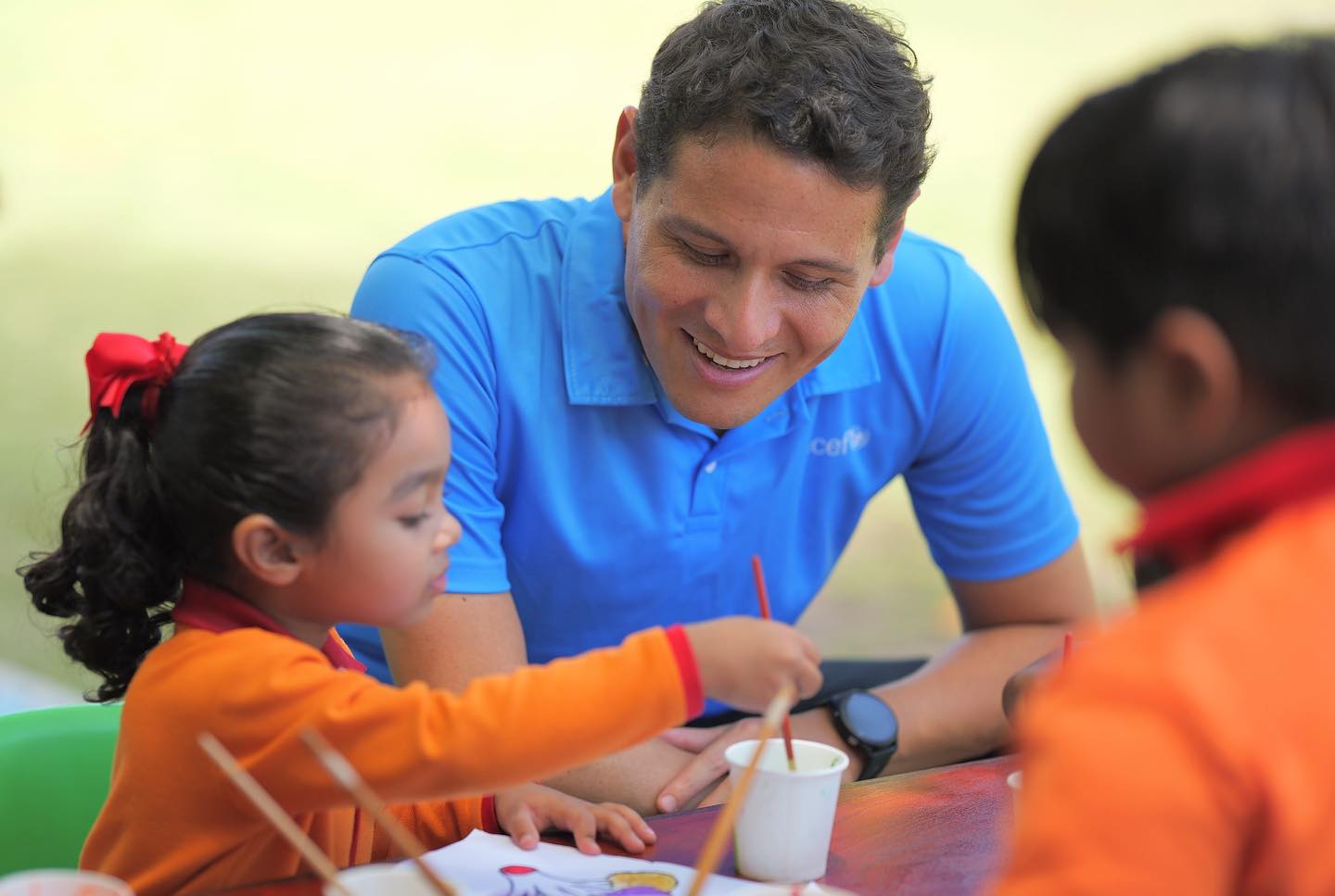 An adult helping children with a painting activity